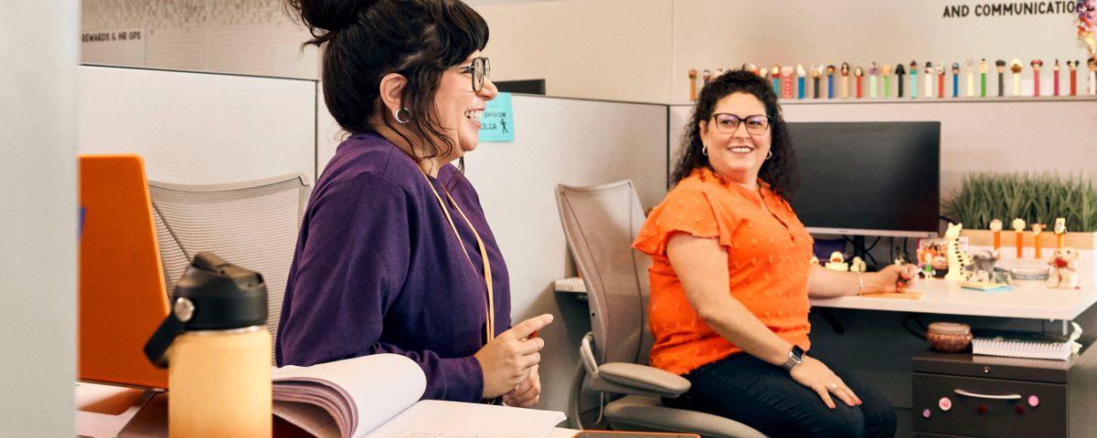Two colleagues engaging in conversation in a bright office environment
