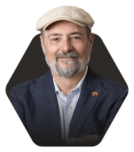 Smiling man in a cap with a welcoming expression featured in a hexagonal frame on a dark background