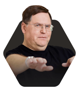 Person gesturing with hands, appearing focused and engaged featured in a hexagonal frame on a dark background