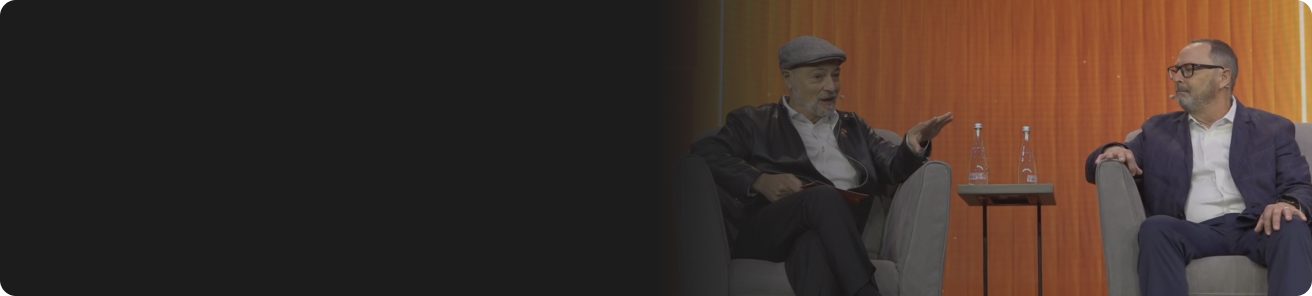 Two individuals engaged in conversation on a stage