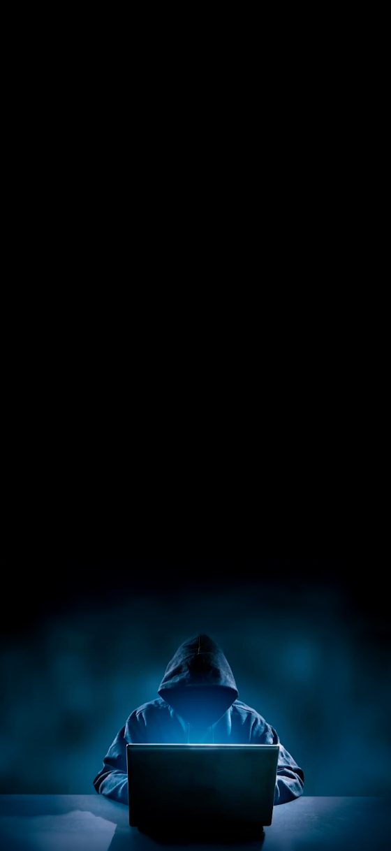 Frau in orangefarbenem Top mit Tablet in einem Gang mit Glaswänden.