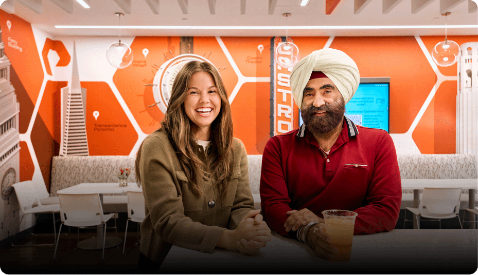 Two smiling individuals in a vibrant, modern cafe setting