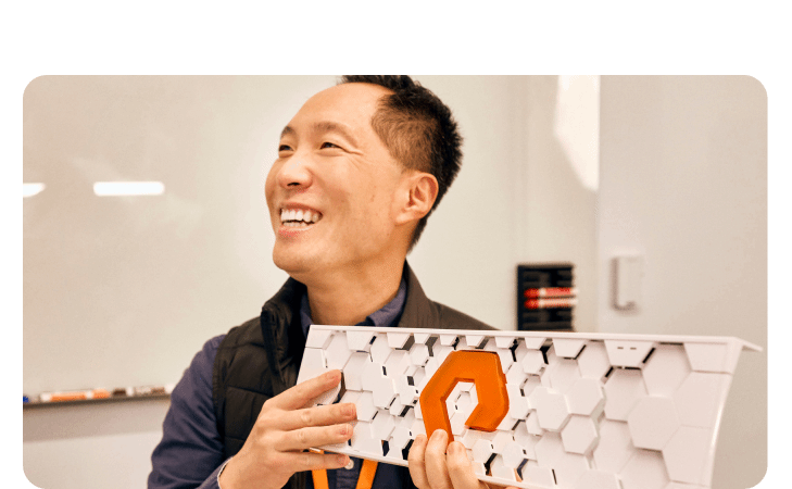 Person holding a design with an orange logo in a creative workspace